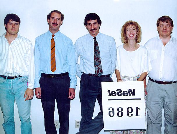 Founders Mark Dankberg, 史蒂夫·哈特和马克·米勒加上两名hg皇冠官网的员工站在一个写着“Viasat 1986”的牌子后面