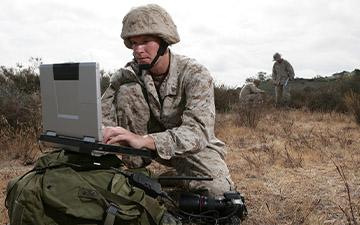 作战人员在战场上利用移动中的卫星通信与笔记本电脑进行通信