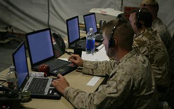 三名男性士兵利用卫星通信通过他们的耳机, 在战术行动中心看笔记本电脑