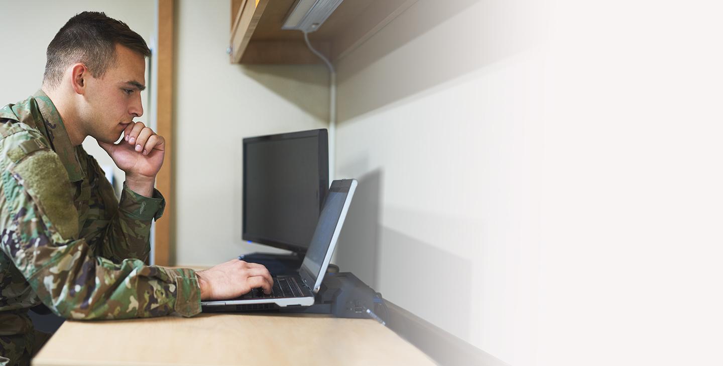 身穿军装的男子坐在书桌前，使用ecrypt技术保护他笔记本电脑上的数据