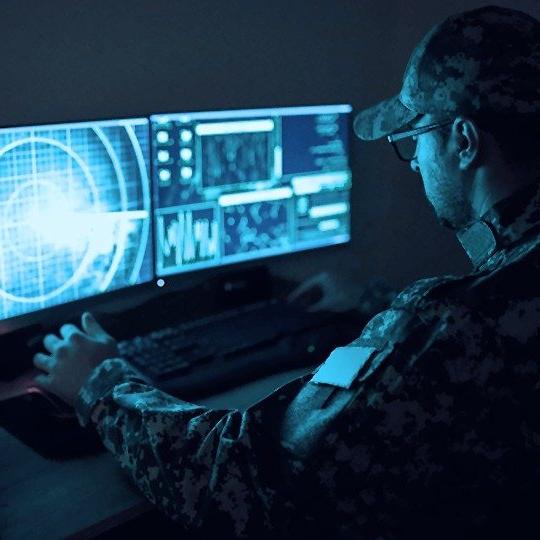 一名身穿绿色军装的男子坐在一台受政府网络安全系统保护的电脑前