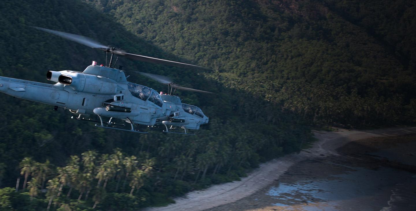 两架军用直升机在海岸线上空飞行