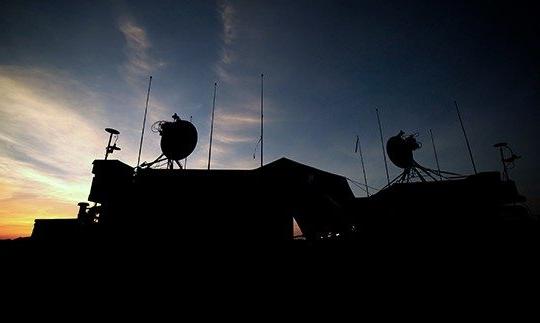 夜间军事建筑的剪影，屋顶上有卫星通信设备