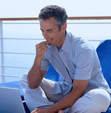 一名男子坐在一艘客船的甲板上，使用装有卫星网络的笔记本电脑